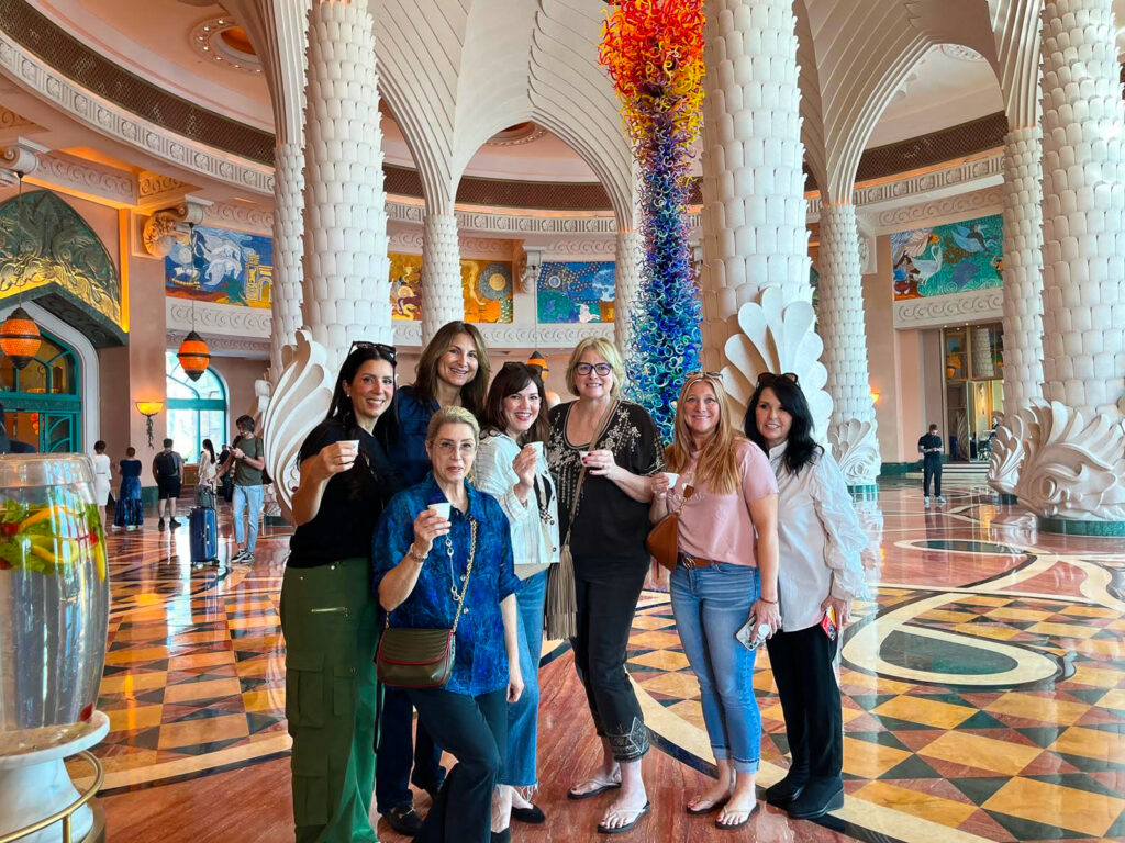 Seven women from Empower Women Media s network pose happily beneath the tall, ornate ceilings inside a building in Dubai.