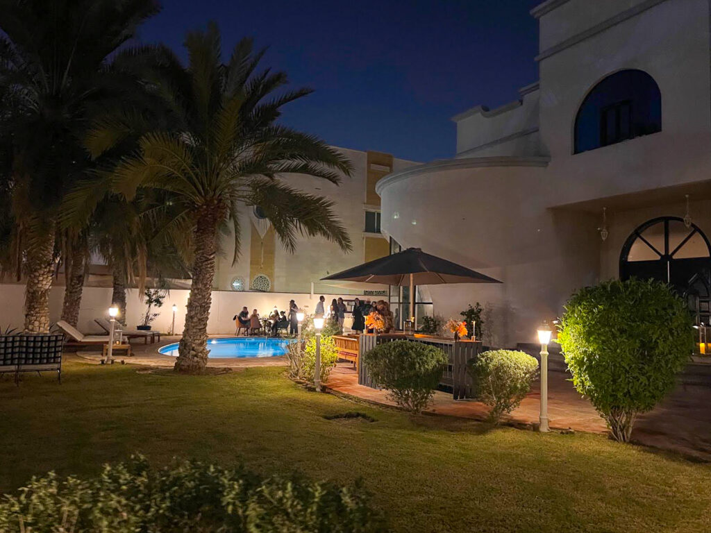 A small welcome party is held at night in the yard of a beautiful house beneath the palm trees.